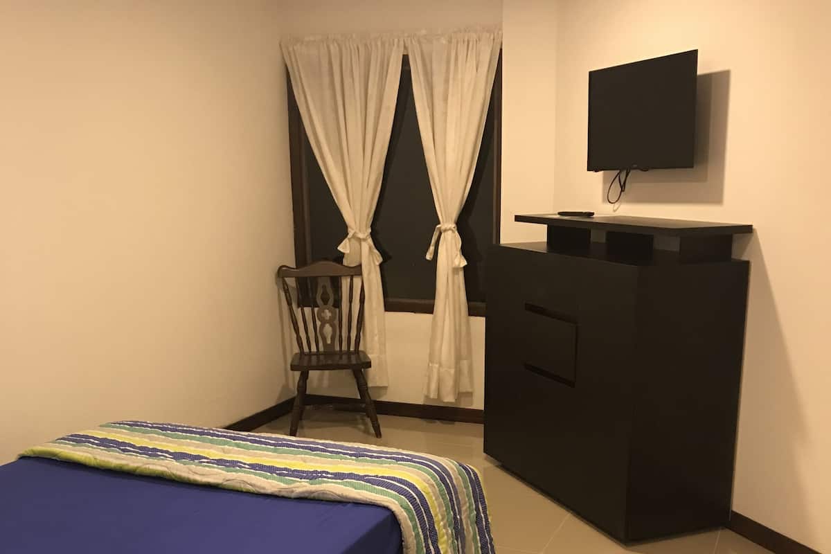 Una camera da letto con un letto, una sedia, una scrivania e una televisione.