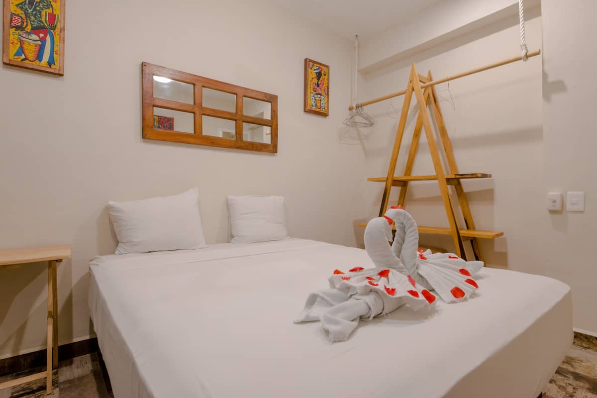 Una habitación de hotel con una cama, una escalera de madera y un espejo en la pared.