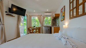 A hotel room with a large bed, a TV mounted on the wall, a dining area with a table and chairs, and a kitchen area. - Casa Luca (Playa del Carmen)