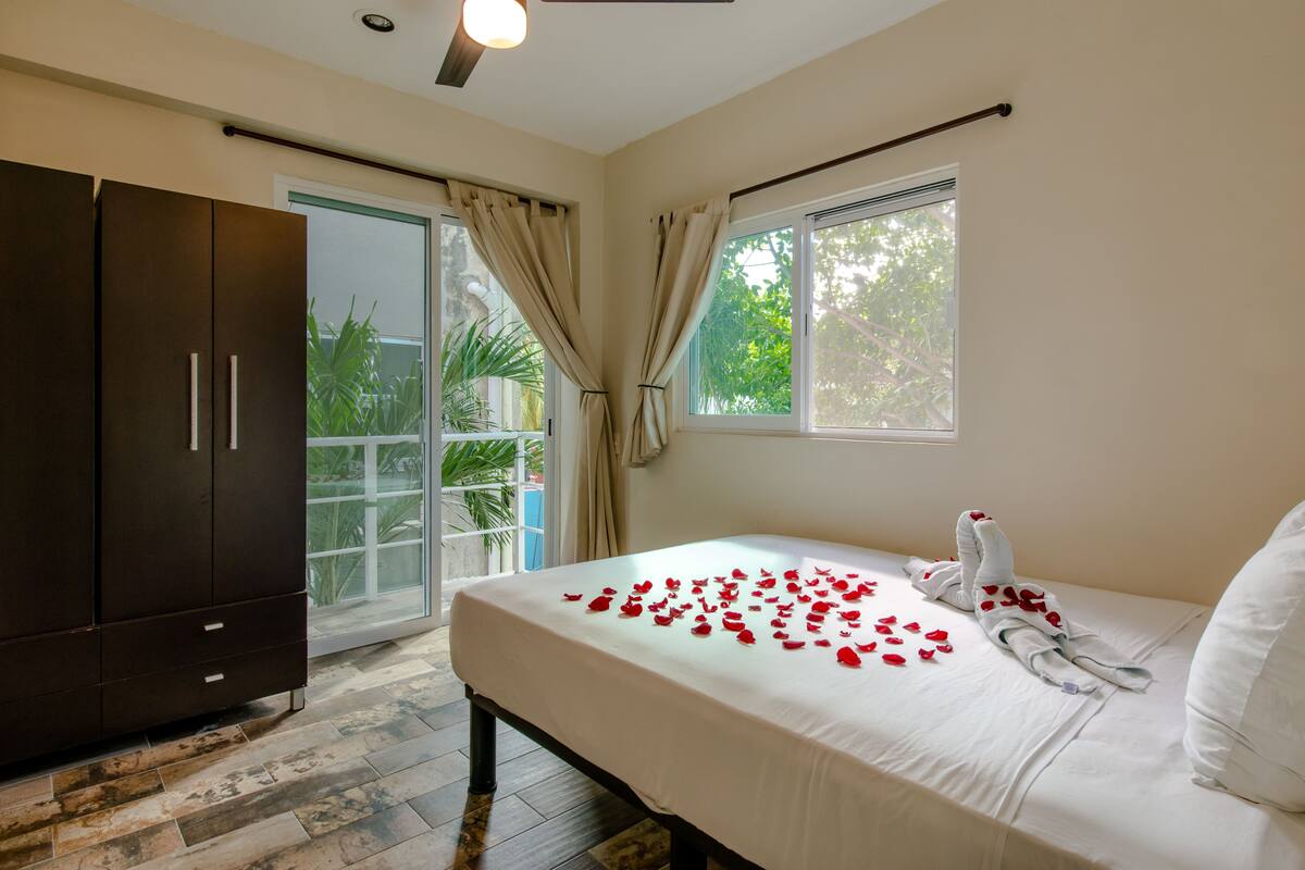 Una habitación de hotel con cama, armario y puerta corrediza de vidrio que da a un balcón.