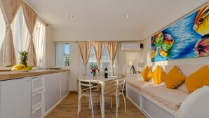 A modern kitchen with a dining area, white cabinetry, and a colorful fish painting on the wall. - Casa Luca (Playa del Carmen)