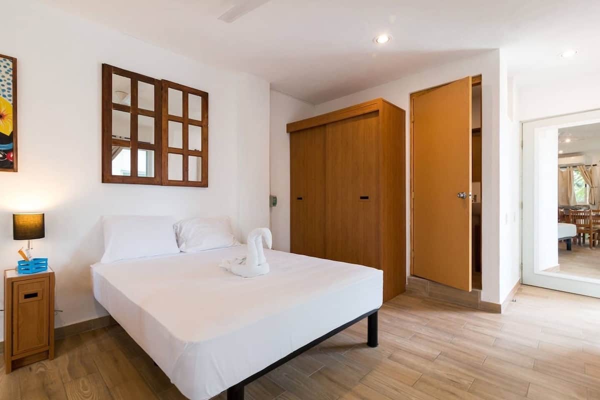 Un dormitorio con cama, armario de madera y mesita de noche.