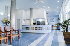 A spacious lobby with a reception desk, wooden chairs, a glass table, and potted plants. - Hotel Lumiar (Coronel Fabriciano)