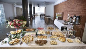 A buffet setup with various food items and a decorative centerpiece. - Hotel Lumiar (Coronel Fabriciano)