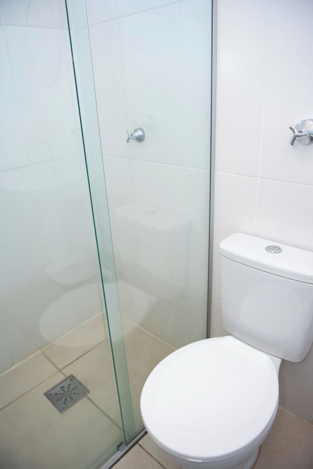 A bathroom with a glass-enclosed shower, a white toilet, and a tiled wall.
