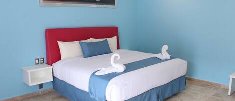 A neatly made bed with a red headboard, white and blue bedding, and a swan-shaped pillow.