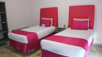 Two beds with red headboards and white bedding in a room with a tiled floor.