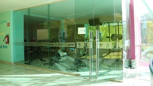 Una palestra con pareti in vetro, attrezzature per esercizi e un estintore a parete.