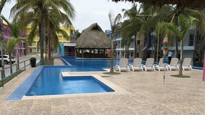 Area piscina con sedie a sdraio e una struttura ricoperta di paglia.