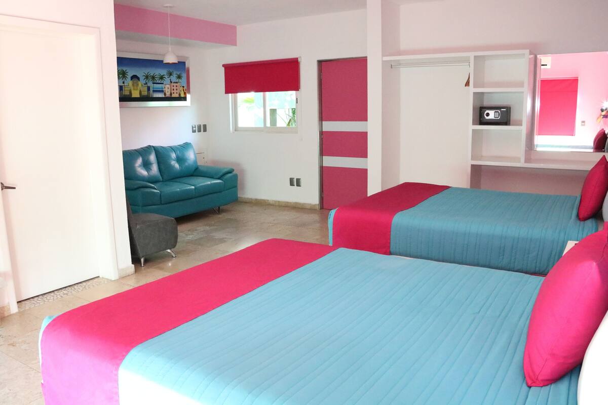 A bedroom with two beds, a sofa, and a TV.