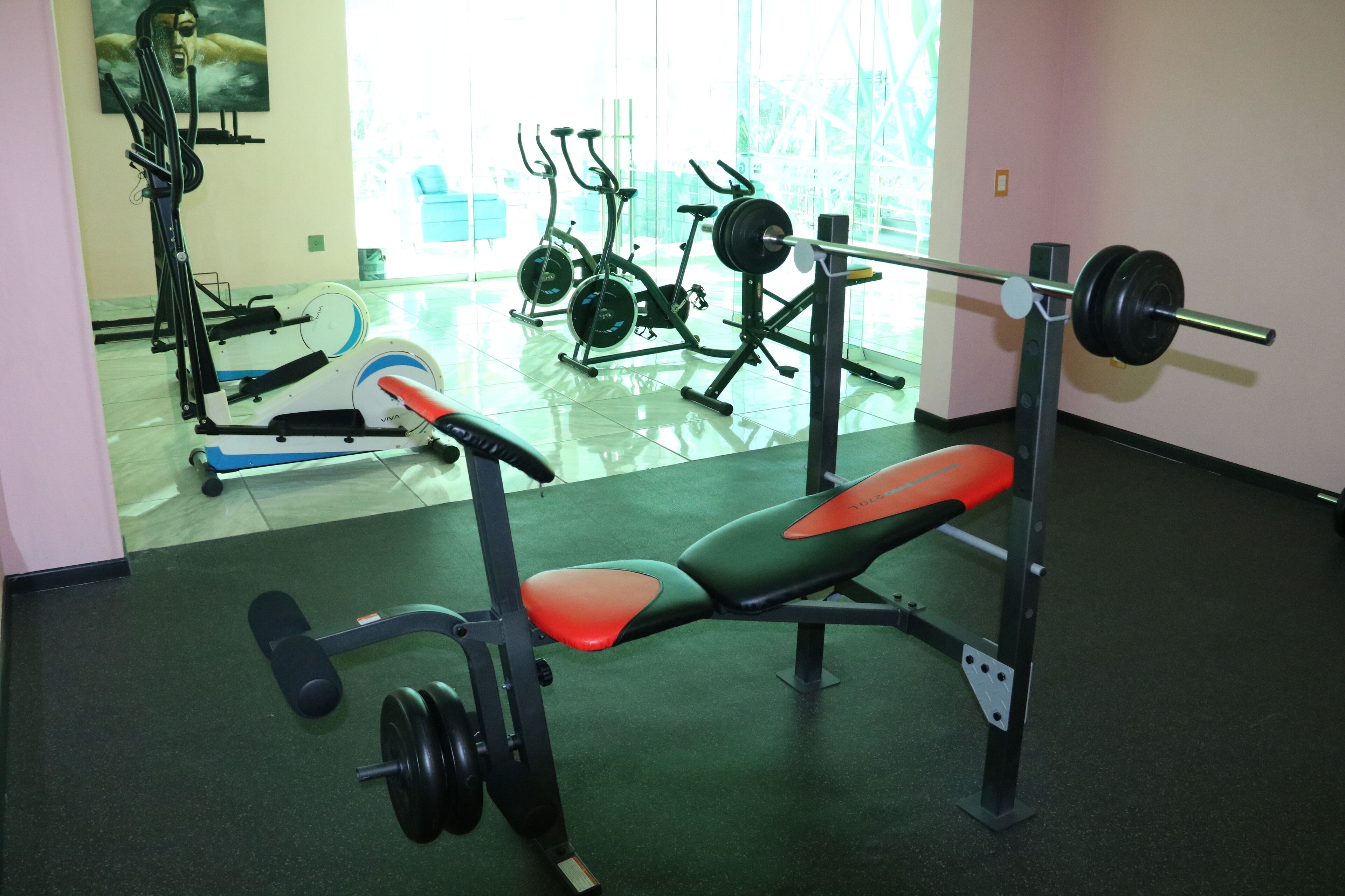 Ein Fitnessraum mit Langhantelbank, Langhantel und Gewichtsplatten.