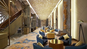 A modern lobby with a central staircase, seating area with sofas and armchairs, and a decorative ceiling. - Hilton Manila Newport World Resorts (Pasay)