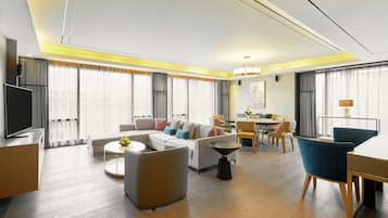 Una habitación de hotel moderna con sala de estar, comedor y televisor.