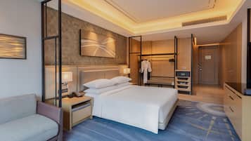 A hotel room with a bed, a seating area, a wardrobe, and a mirror.