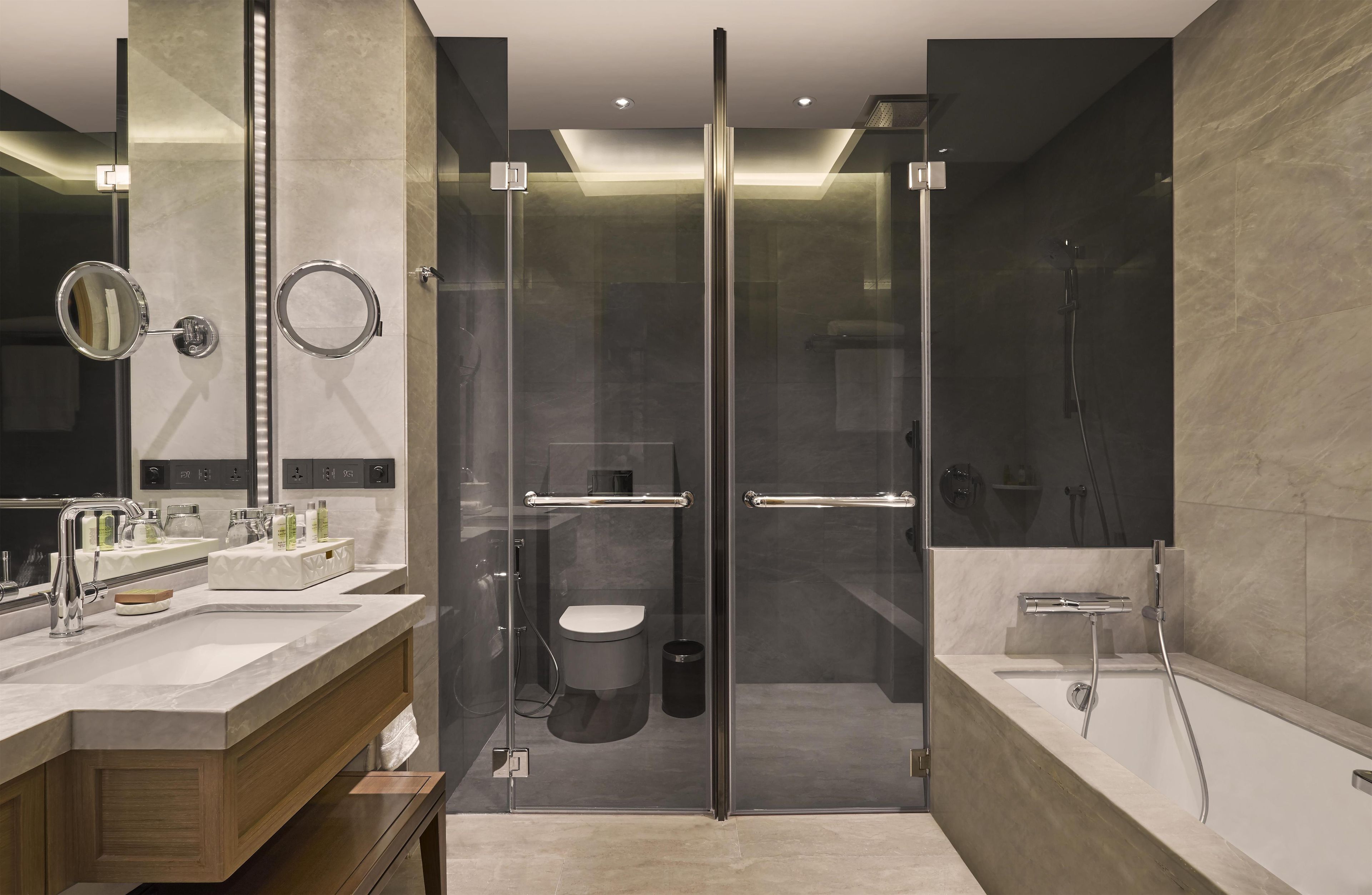 A modern bathroom with a glass-enclosed shower, a vanity with a mirror, and a bathtub.