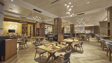 A spacious restaurant with multiple dining areas, wooden flooring, and hanging pendant lights.