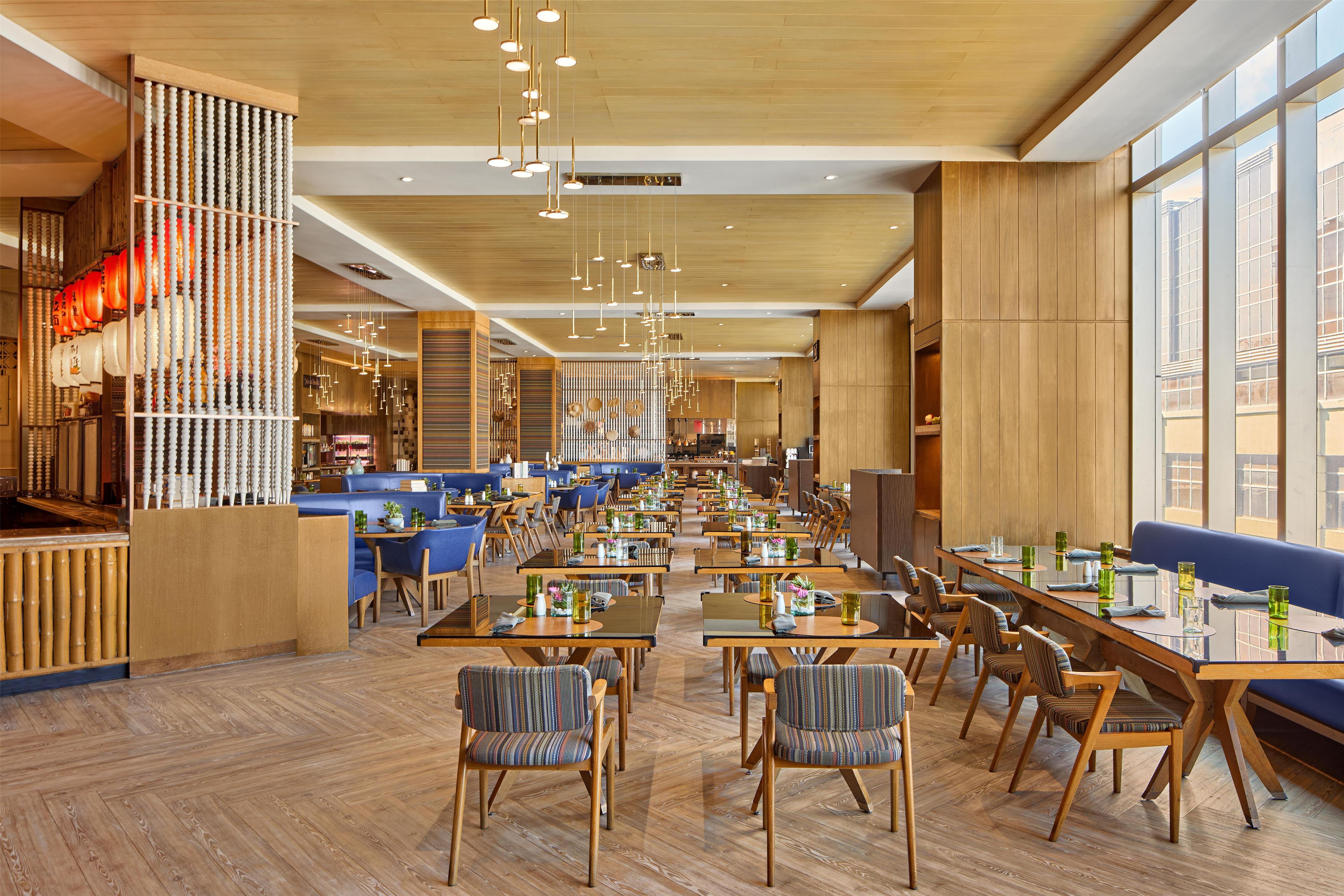 A spacious restaurant with high ceilings, wooden floors, and a variety of seating arrangements including tables and booths.