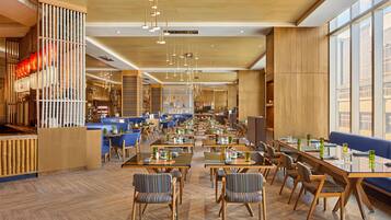 A spacious restaurant with high ceilings, wooden floors, and a variety of seating arrangements including tables and booths.