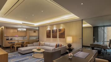 Habitación de hotel moderna con sala de estar, una mesa de comedor, sofá, escritorio y un ventanal grande.