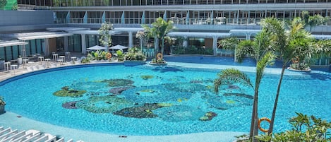Zona de piscina de hotel con piscina azul cristalina, sillas de descanso y palmeras.