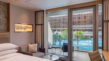 A hotel room with a large sliding glass door leading to a balcony with a pool.