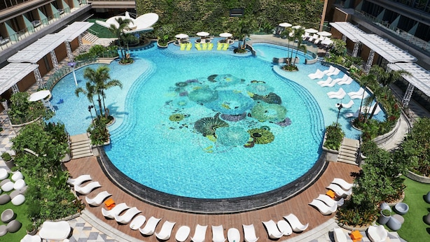 A large circular pool with multiple seating areas and palm trees. - Hilton Manila Newport World Resorts (Pasay)