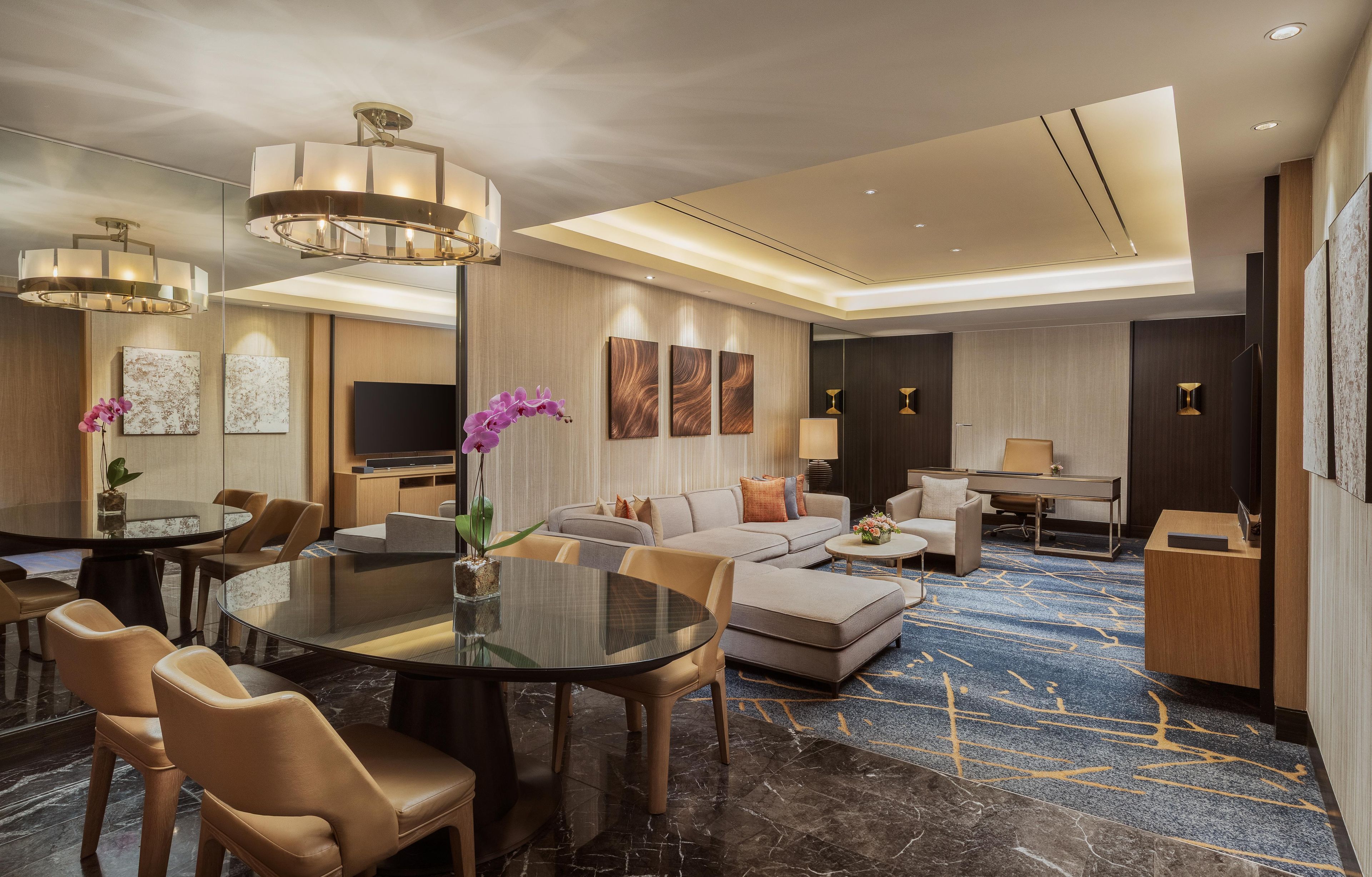 Habitación de hotel moderna con comedor, sofá, televisión y escritorio.