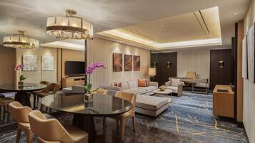 Habitación de hotel moderna con comedor, sofá, televisión y escritorio.