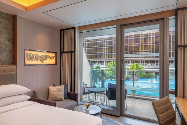 A hotel room with a large sliding glass door leading to a balcony with a pool view. - Hilton Manila Newport World Resorts (Pasay)