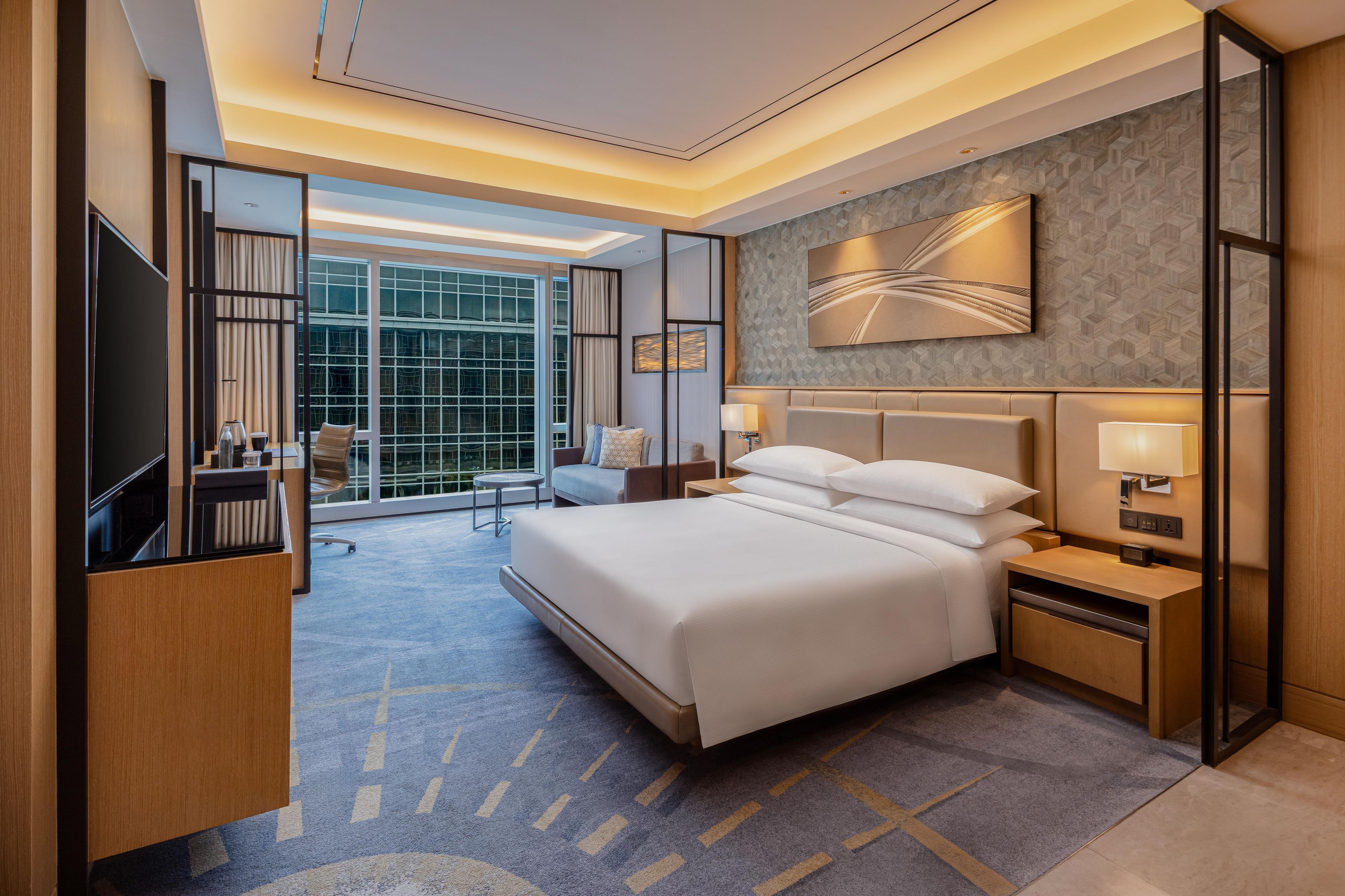 Habitación de hotel con una cama grande, un escritorio, una silla y un televisor.