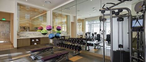 A modern gym with weightlifting equipment, treadmills, and exercise balls.