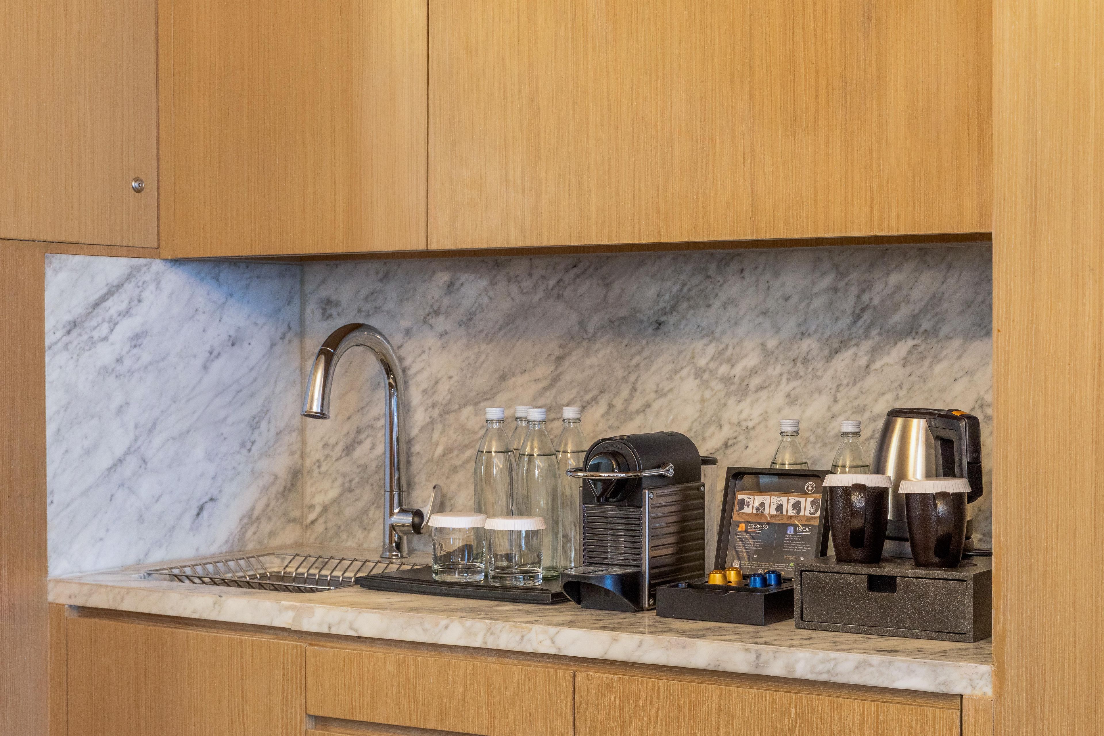 Una cocina con encimera de mármol, cafetera y hervidor.