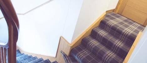 A staircase with a wooden handrail and a fire alarm on the wall.
