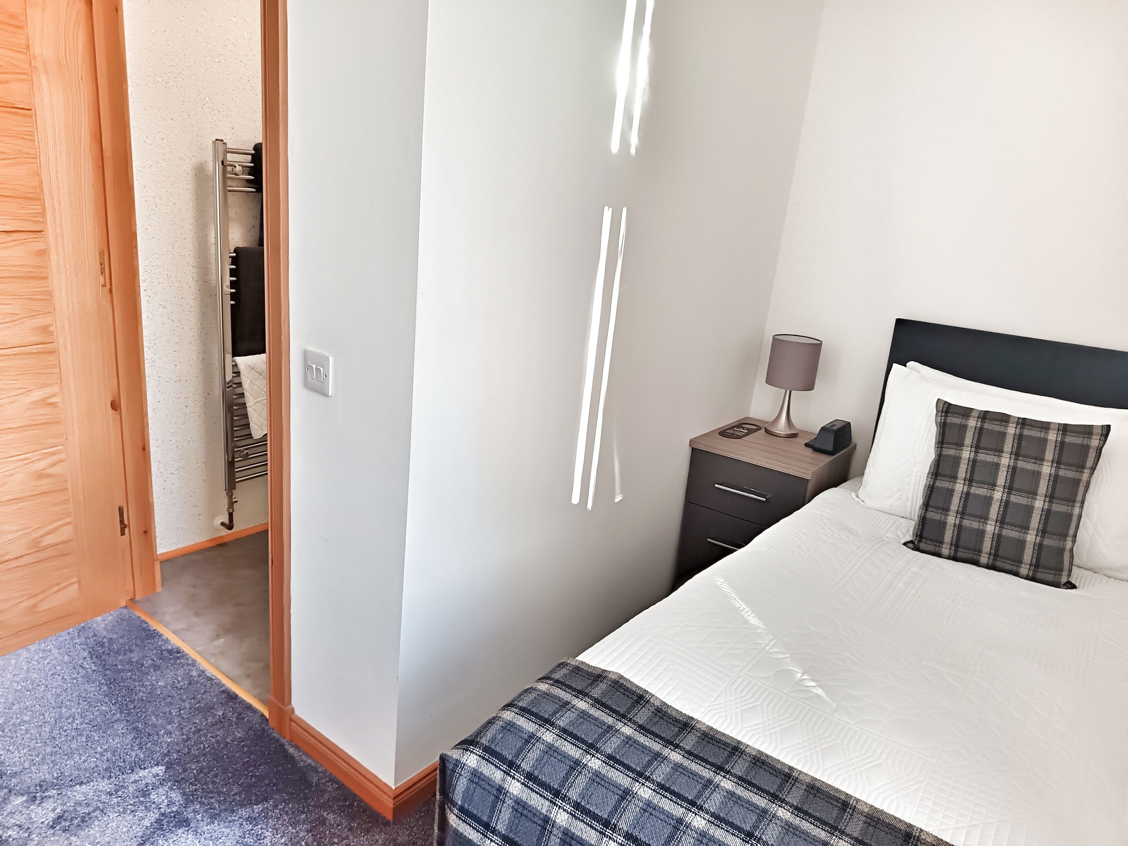 Une chambre à coucher avec un lit, une table de chevet, une lampe et une armoire.