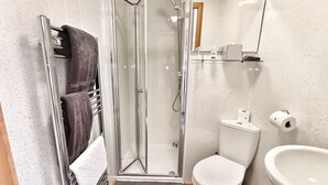Un baño pequeño con ducha de vidrio, inodoro y lavamanos.