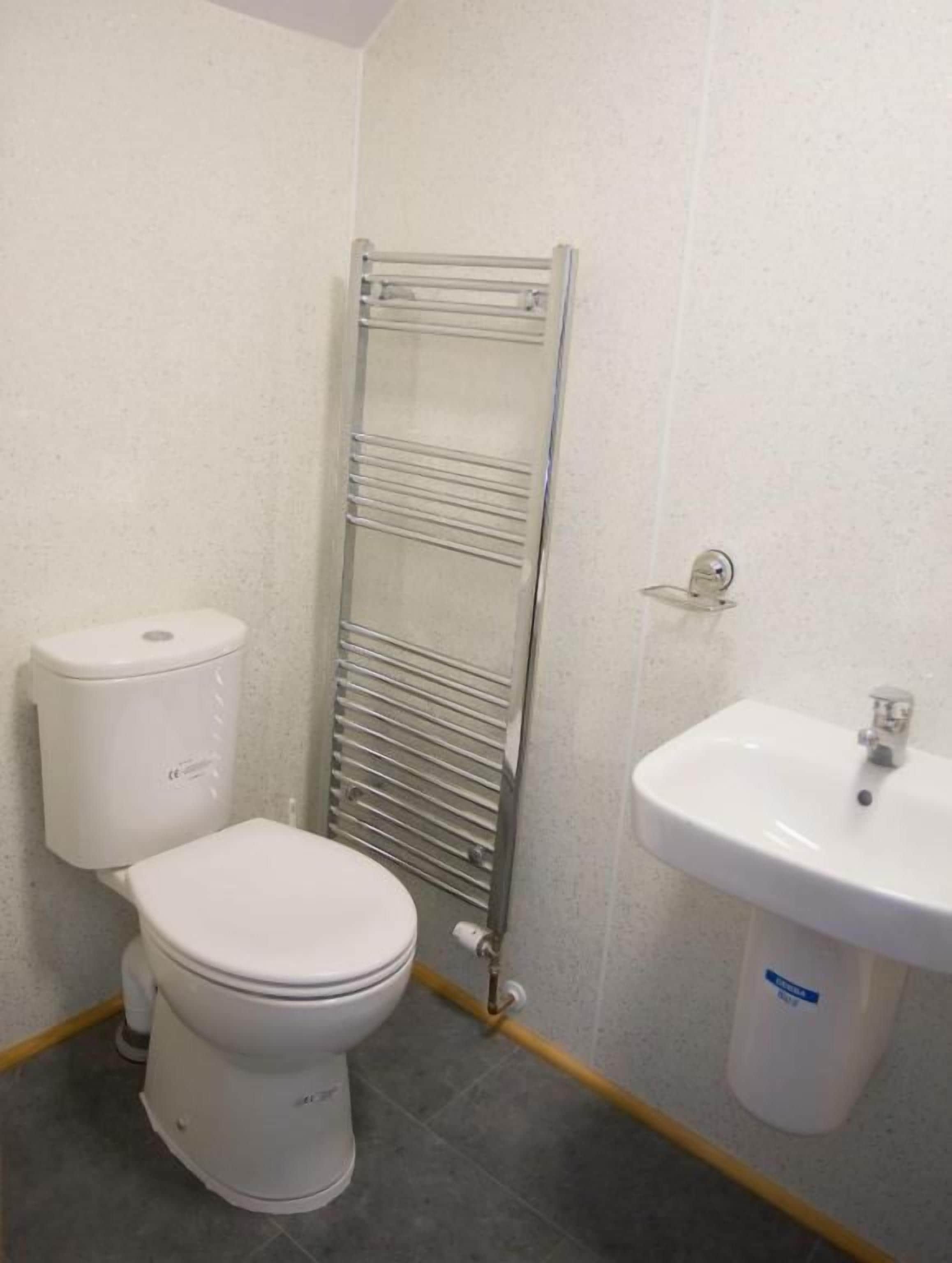 Un baño con inodoro, toallero y lavamanos.