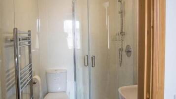 Un baño moderno con ducha compartimentada con vidrio, inodoro y lavamanos.