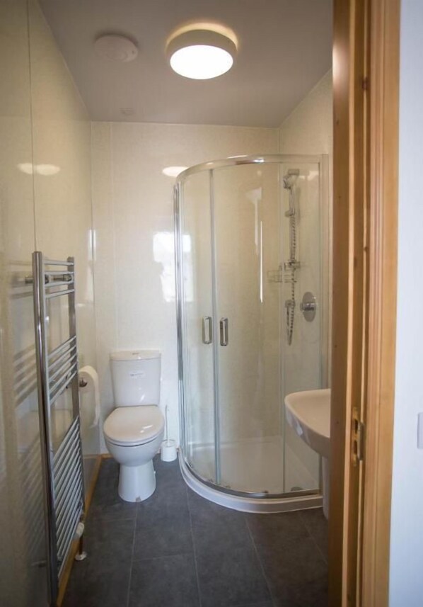 Un baño moderno con ducha compartimentada con vidrio, inodoro y lavamanos.