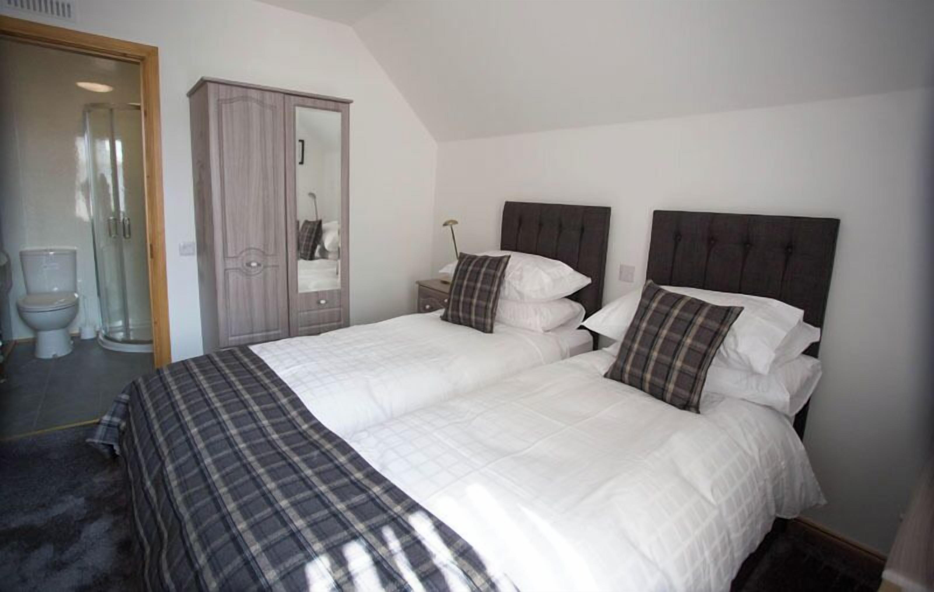 A bedroom with a large bed, two bedside tables, a wardrobe, and a mirror.