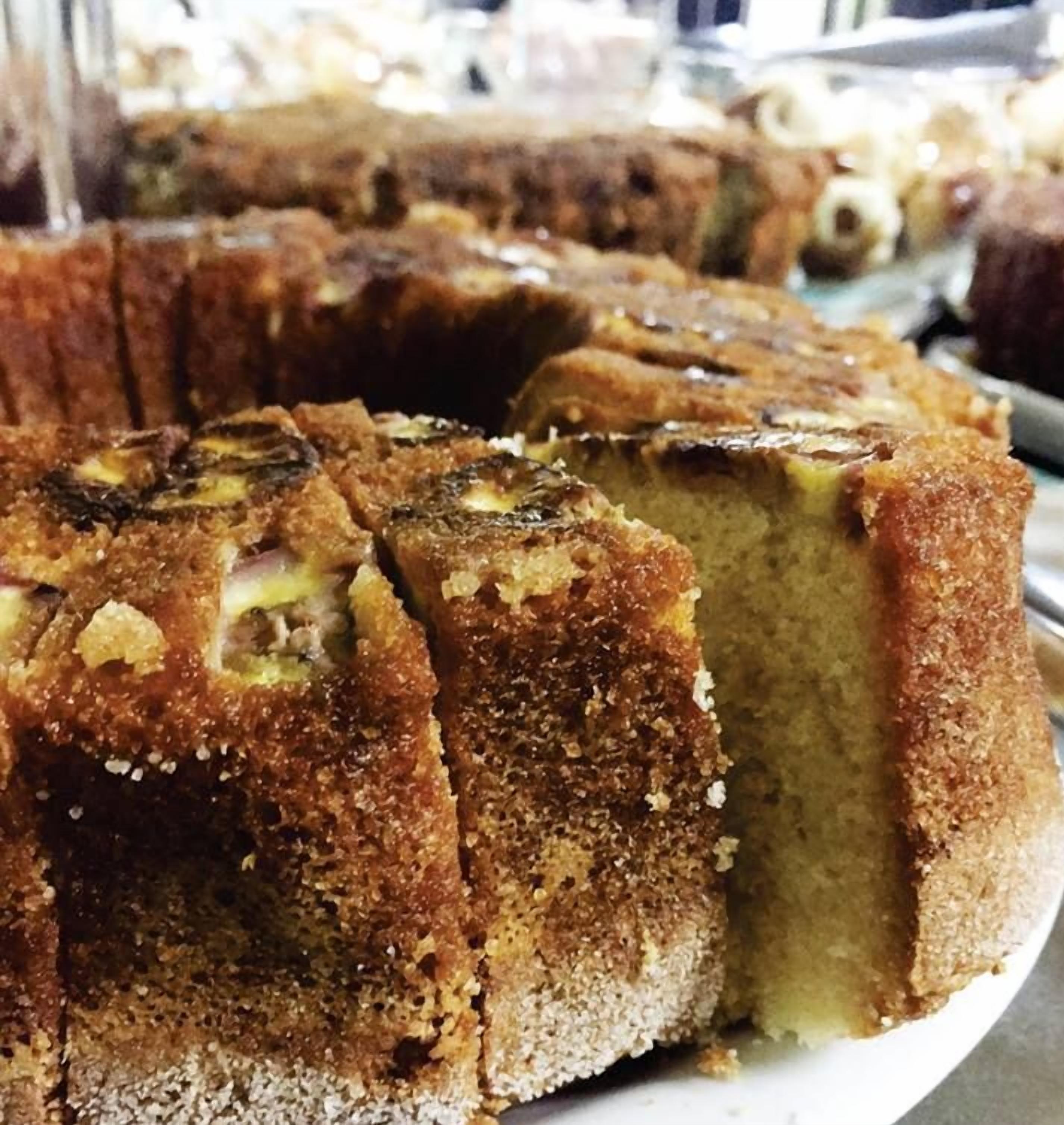 Un gâteau à la croûte dorée et dont on peut voir la garniture, qui pourrait être à base de fruits ou de noix, présenté sur une assiette blanche.