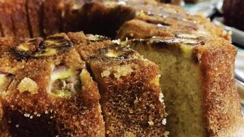 A cake with a golden-brown crust and a visible filling, possibly a fruit or nut center, on a white plate.