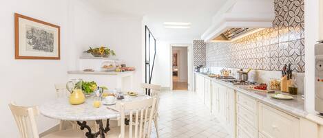 A bright kitchen with white cabinets, a marble countertop, and a patterned backsplash.