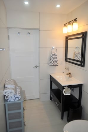 Une salle de bain avec une porte blanche, un lavabo avec un miroir et un porte-serviettes.