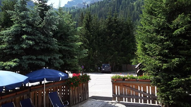 A parking area with a wooden fence, blue chairs, and a blue umbrella. - Chalet Brigitte (Livinallongo del Col di Lana)