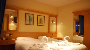 A hotel room with a large bed, a bedside table, a nightstand, a mirror, and two framed pictures on the wall. - Chalet Brigitte (Livinallongo del Col di Lana)