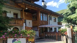 A wooden chalet with balconies, a sign for 'Chalet Brigitte' offering apartments and breakfast, and a view of a mountain. - Chalet Brigitte (Livinallongo del Col di Lana)