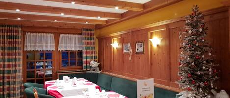 A cozy restaurant with wooden walls, a Christmas tree, and tables set for dining.