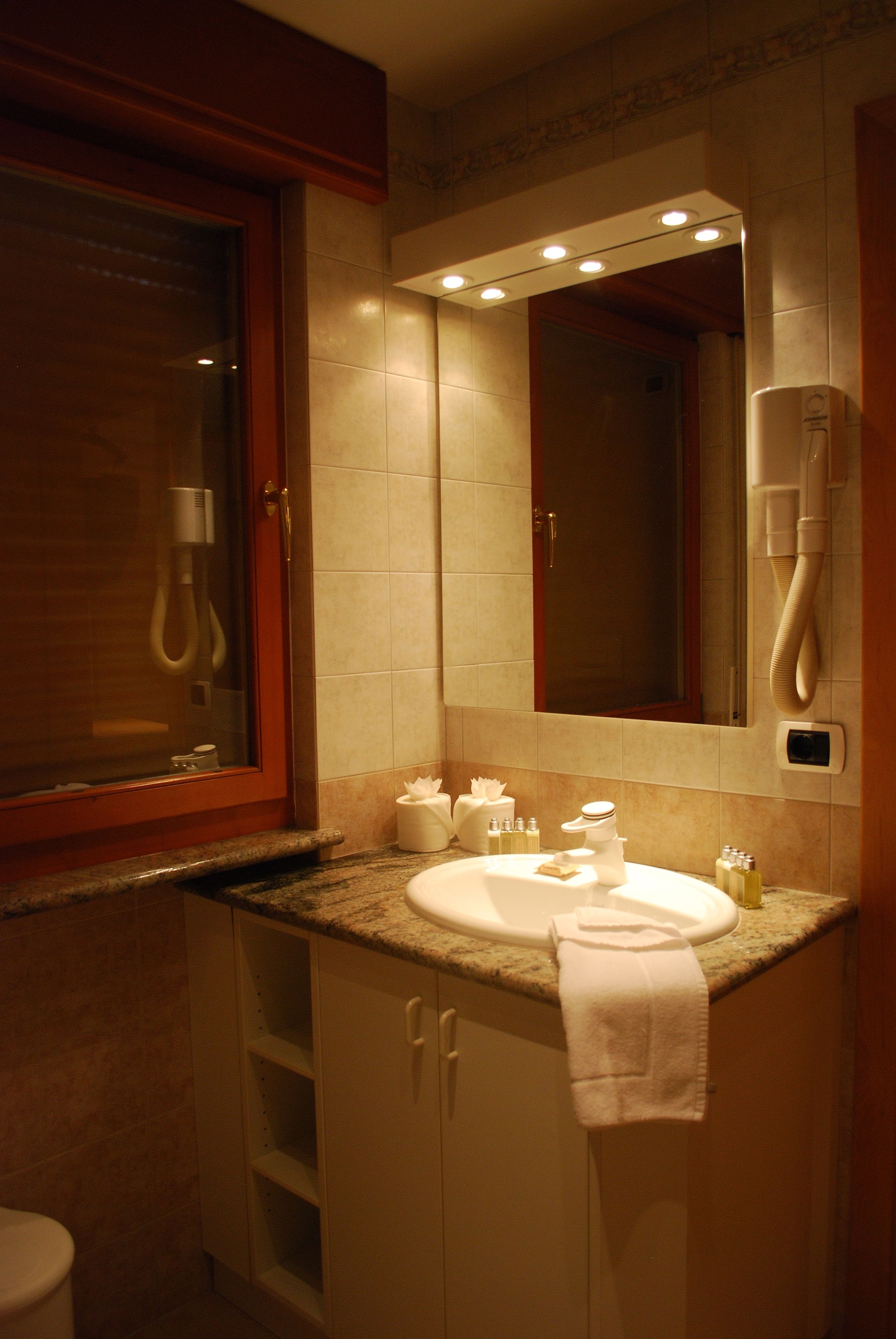 A bathroom with a sink, mirror, and a handheld showerhead.