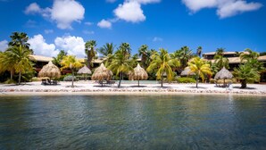 A resort with a pool, palm trees, and thatched umbrellas. - Spanish Water Apartments (Jan Thiel)
