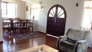 Una sala de estar con piso de madera, un comedor con mesa y sillas, un gran arco y un tapete estampado.